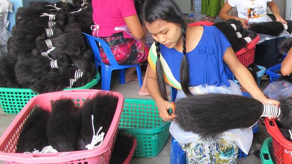 Women in Myanmar painstakingly sort hair in to bunches of similar lengths