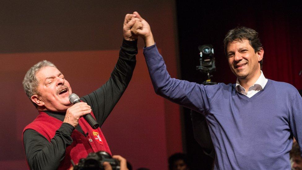 Luiz Inacio Lula da Silva (left) raises the hand of Fernando Haddad during a campaign rally in 2012