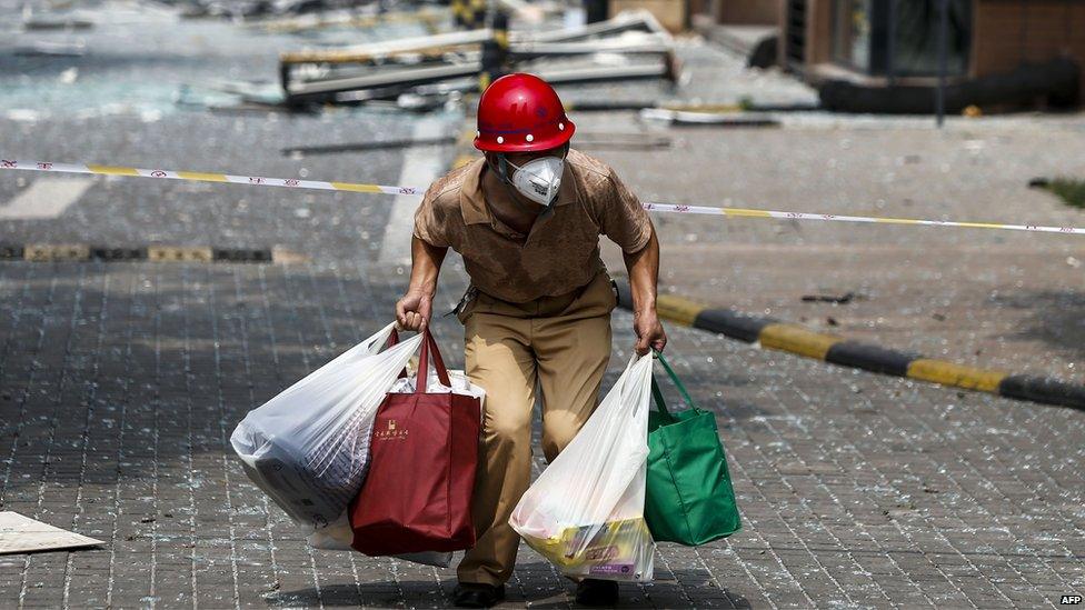 A victim of the explosions carrying his belongings walks out of his home in a residential area