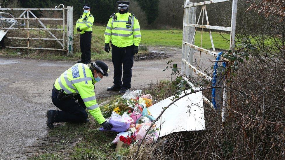 A police officer lays flowers left by members of the public