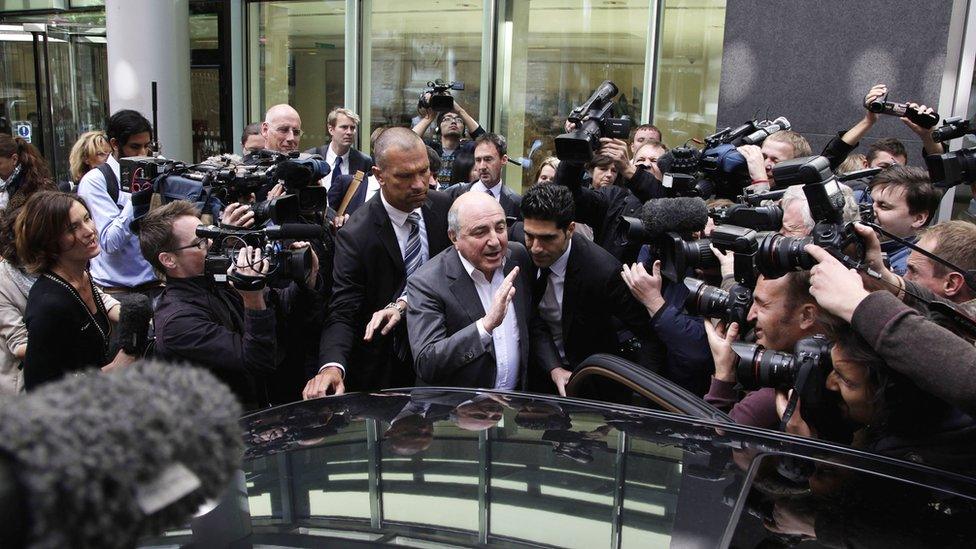 A huge crowd of cameramen push against security personnel escorting an older Berezovsky to his car outside court