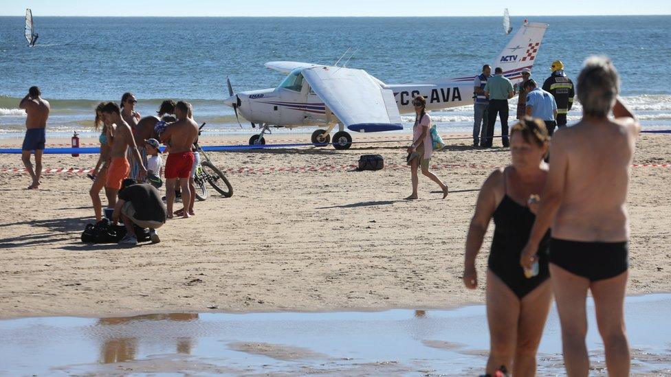 Onlookers watch the recovery of a light plane after two people were killed after the plane made an emergency on Sao Joao beach on Costa de Caparica in Almada, Portugal, 02 August 2017