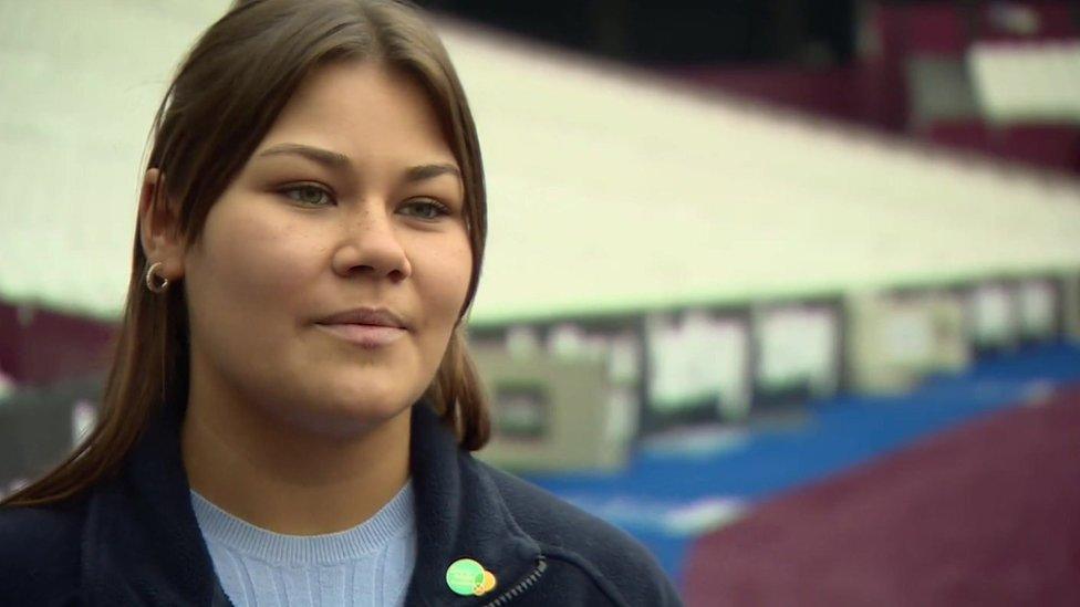 Image of Daisy Blondell, who has dark hair and is standing in front of seating at the stadium