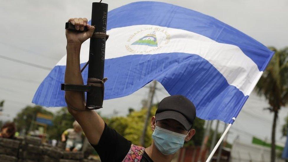 A young protester raises his artisan weapon and the Nicaraguan national flag, in Managua, Nicaragua, 15 June 2018.