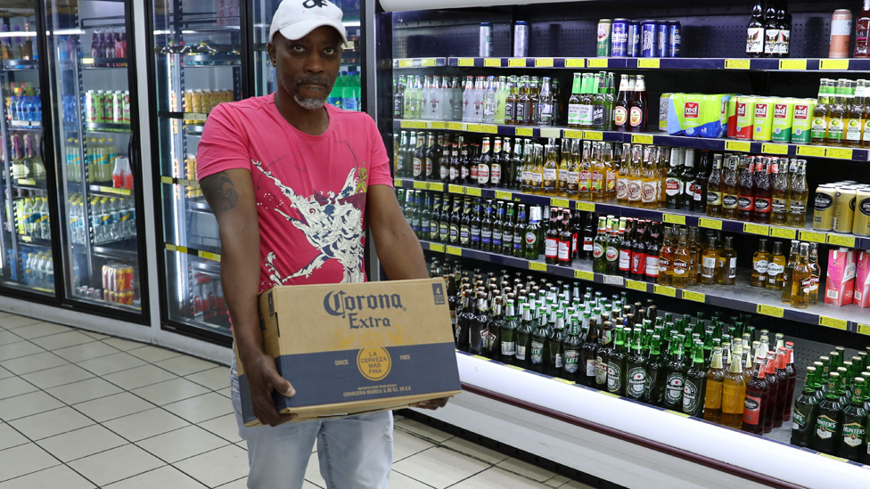 A shopper carries a box of alcohol with the words "Corona extra" ahead of a nationwide lockdown for 21 days to try to contain coronavirus in Johannesburg, South Africa