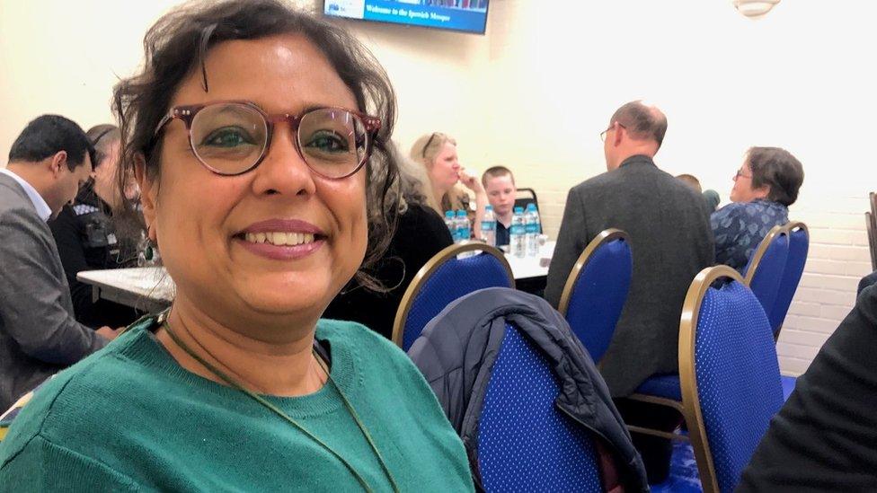 A woman sat at a table in front of others behind her.