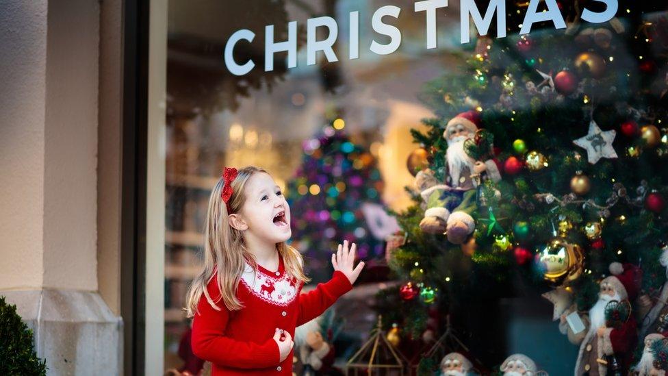 Child standing beside a Christmas tree