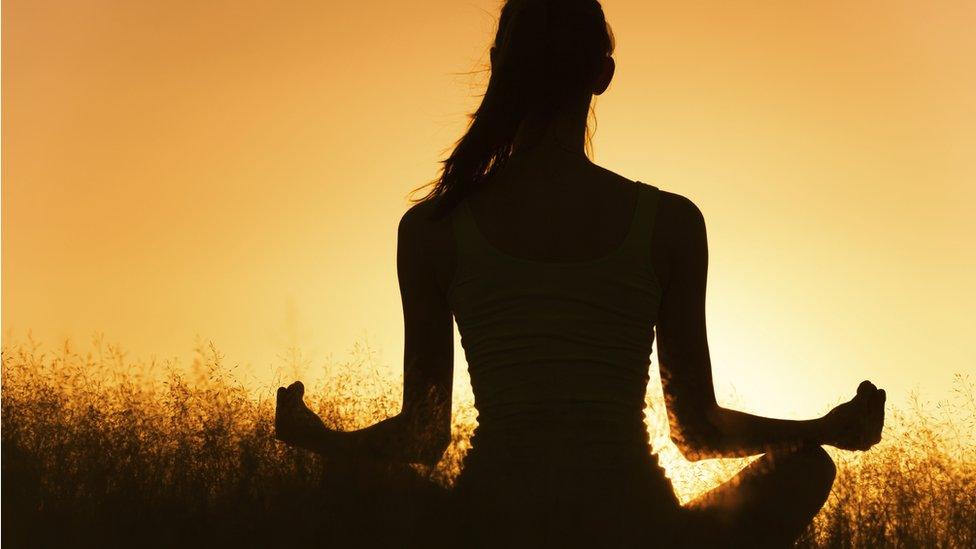 women meditating at sunset