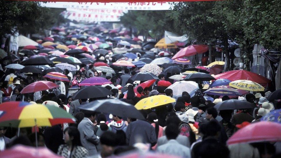 People attending a festival in China hold umbrellas