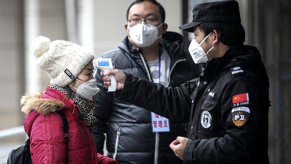 Security personnel check the temperature of passengers in the Wharf at the Yangtze River on January 22, 2020 in Wuhan