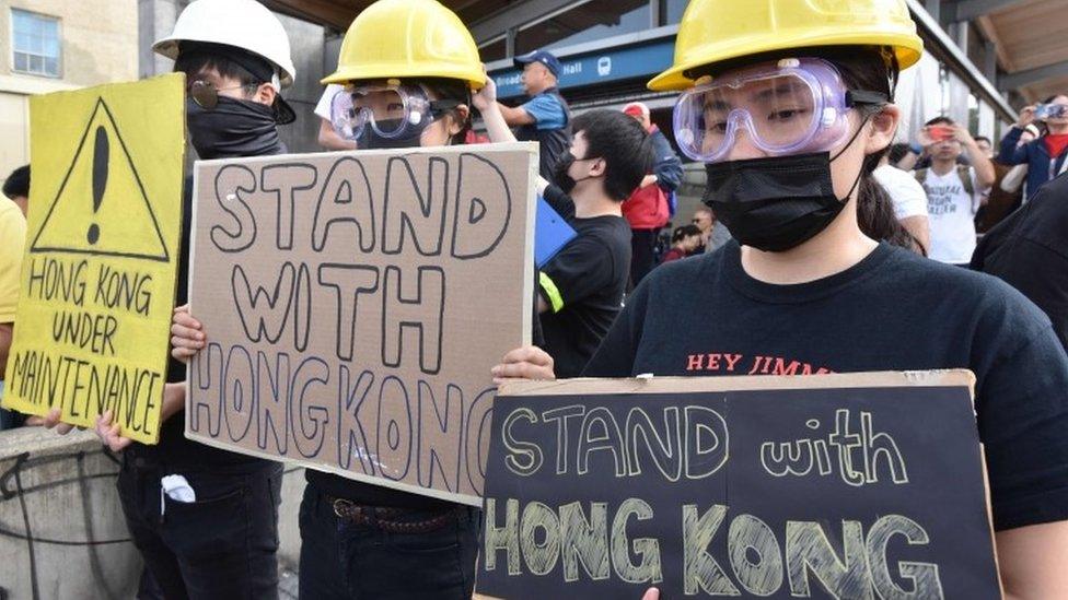 Hong Kong pro-democracy supporters hold signs during a rally in Vancouver