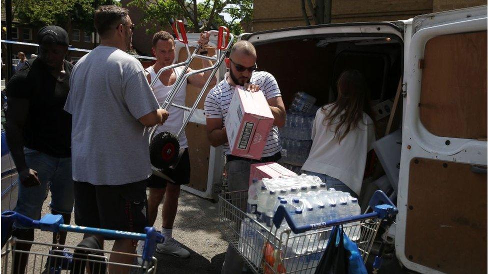 People unload water and supplies from a van at a temporary relief centre