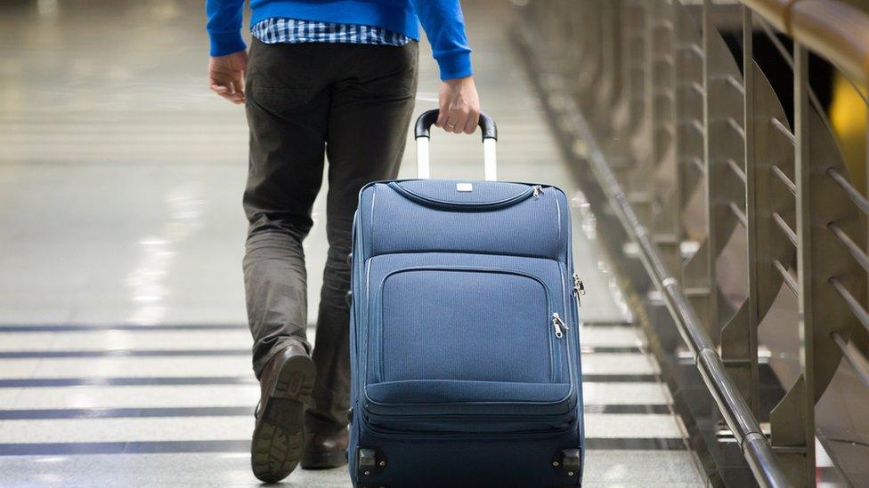 Man wheeling suitcase