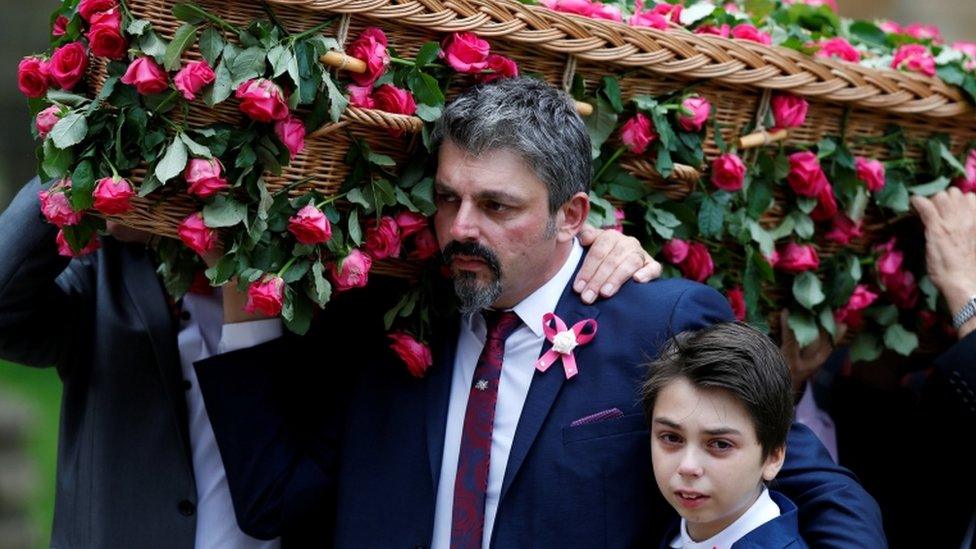 Andrew Roussos puts a hand around his son Xander as he carries his daughter's coffin