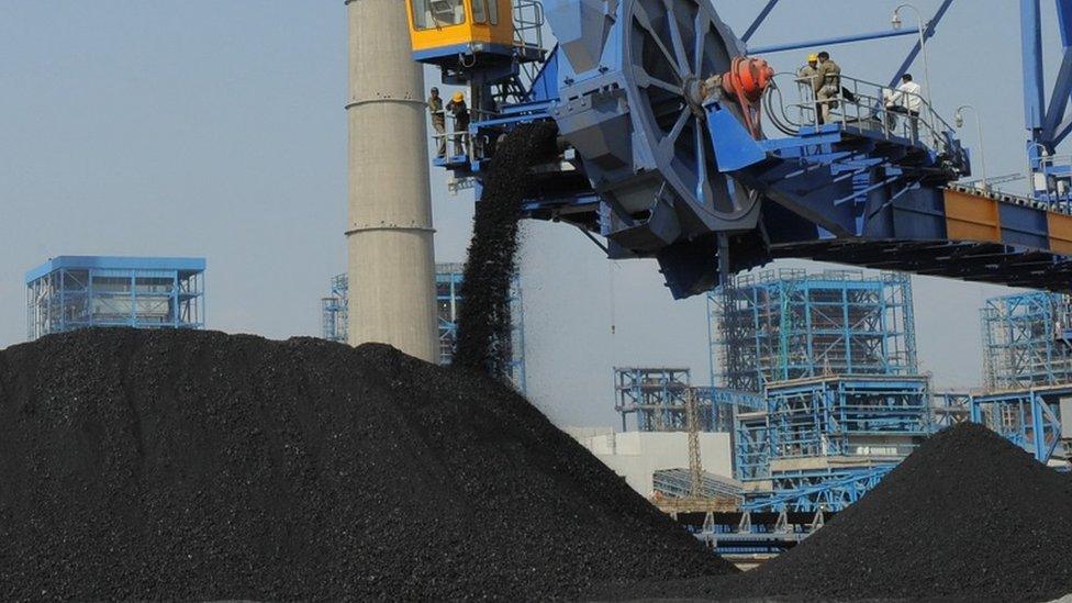 Workers use heavy machinery to sift through coal at the Adani Power company thermal power plant at Mundra