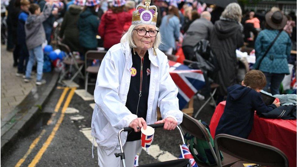 A woman wearing a crown attends a street party in Ashby-de-la-Zouch, England