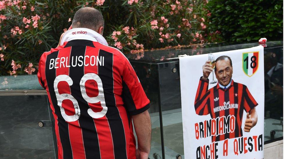 A supporter of the AC Milan football club wears a jersey of the honorary president of the club Silvio Berlusconi