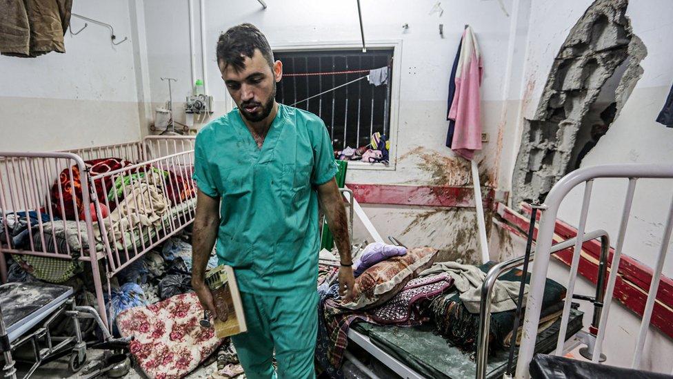 A medic inspects the damage to a room in the maternity building of Nasser Hospital in Khan Younis, in the southern Gaza Strip (17 December 2023)