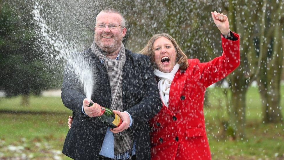 Ellie Land and Karl Ward celebrating their lottery win by opening a bottle of champagne