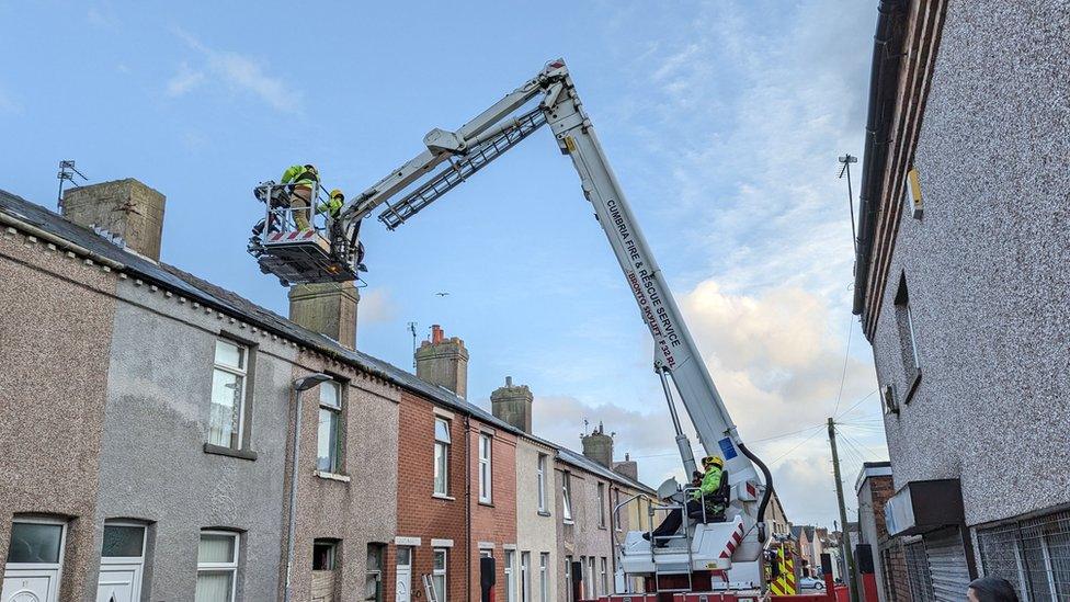 Firefighters on a cherry picker get up to the roof