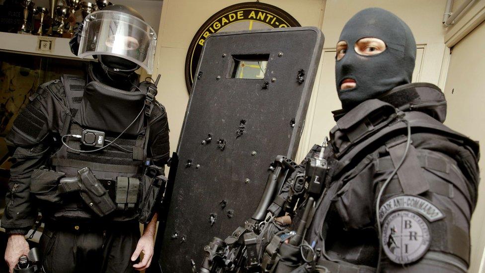 French police officers with a shield damaged by many bullets