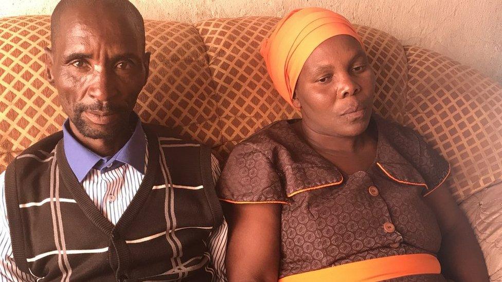 Michael's parents, James Komape and Rosina Komape, sit together on a sofa at their home.