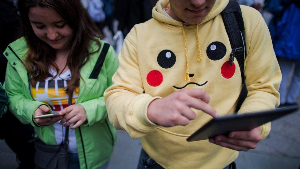 Young people playing Pokemon Go with one dressed in a Pikachu hoodie