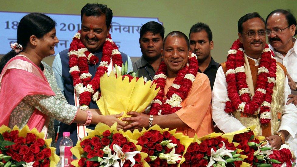 Senior Leader of India's Bharatiya Janata Party (BJP) M. Venkaiah Naidu (R) Uttar Pradesh BJP Leaders Prasad Maurya (2L) and Dinesh Sharma (2R) look on as Yogi Adityanath (C) is presented with a floral bouquet during a ceremony in Lucknow on March 18, 2017, after he was picked as the new Chief Minister of the northern Indian state of Uttar Pradesh