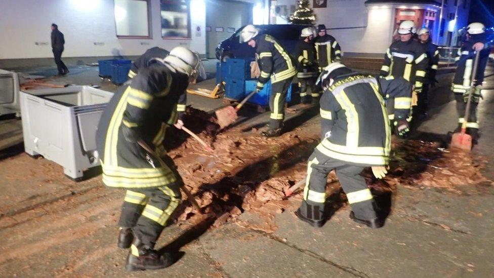 Firefighters cleaning up chocolate from a road.