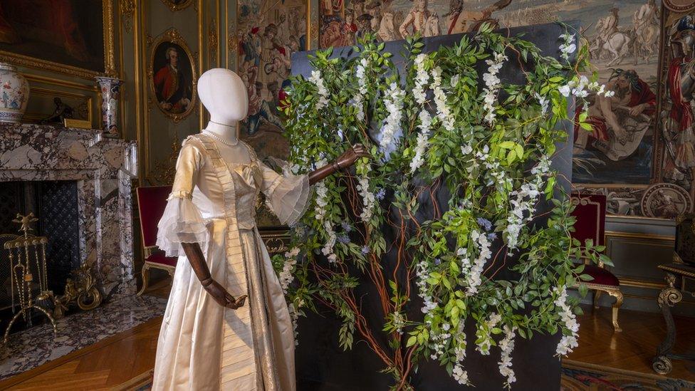 Mannequin with a period dress in front of artificial wisteria