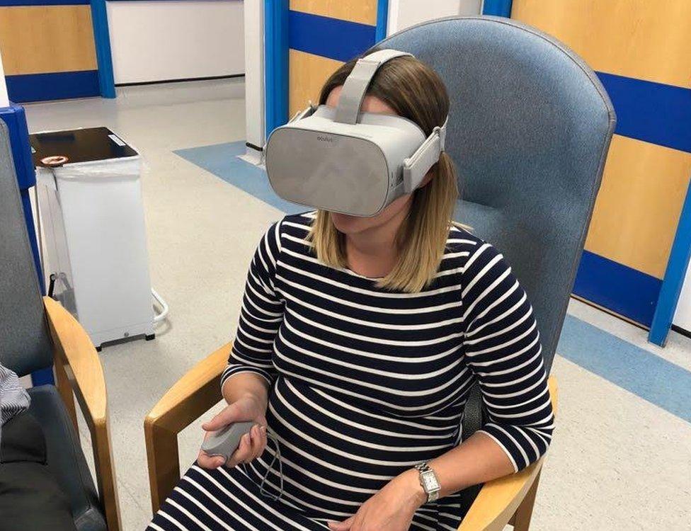 Pregnant woman sitting in a hospital chair wearing a VR headset