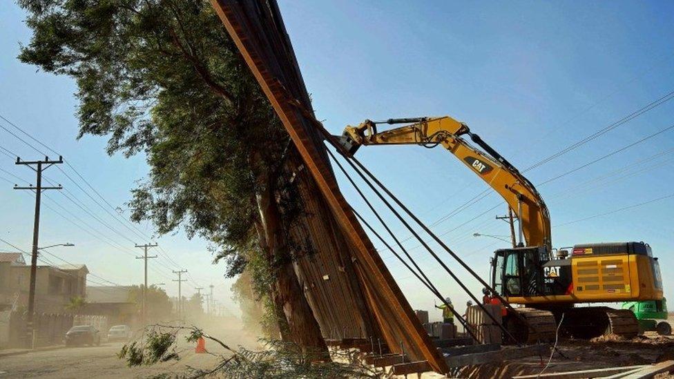 A construction crew works on a fallen section of the US-Mexico border wall as seen from Mexicali, Baja California state, Mexico