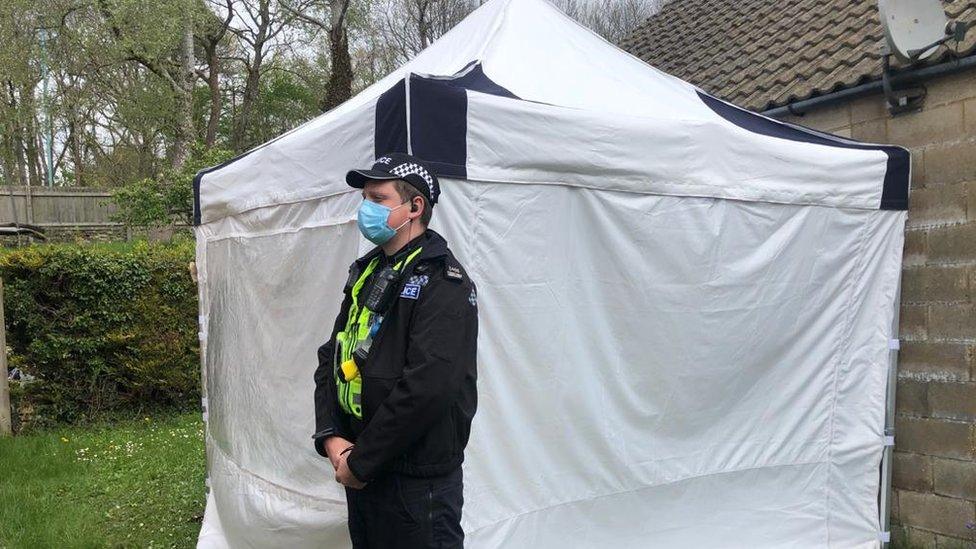 Police officer stands outside crime scene tent