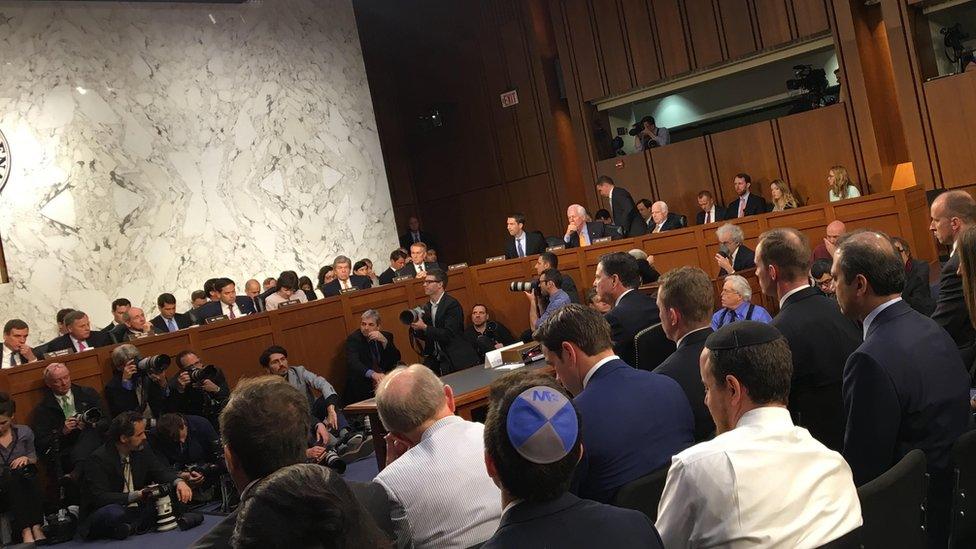 Mr Comey testifies in front of a bank of photographers