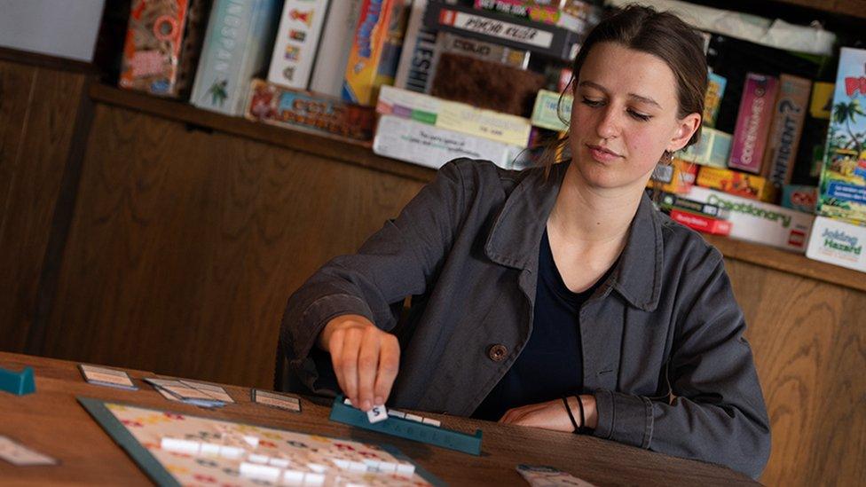 Anna places a tile on the Scrabble board