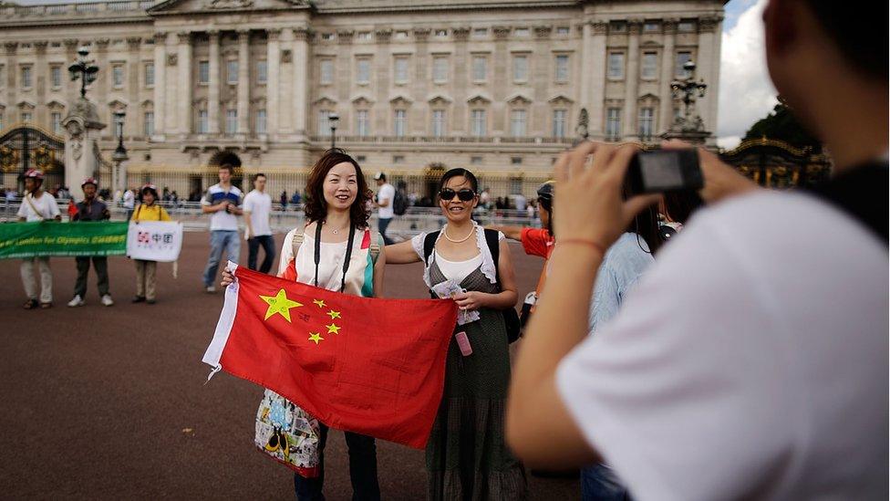 Chinese tourists have their pictures taken outside Buckingham Palace on July 29, 2012 in London, England