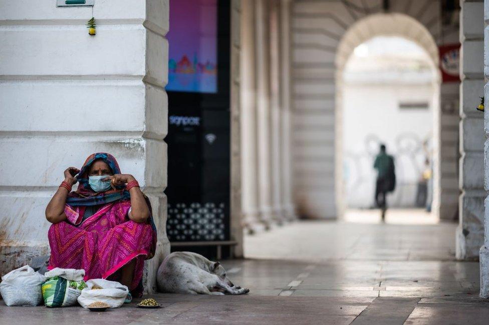 A bird feed vendor wearing a facemask as a preventive measure against the COVID-19 coronavirus waits for customers at a market area in New Delhi on March 19, 2020