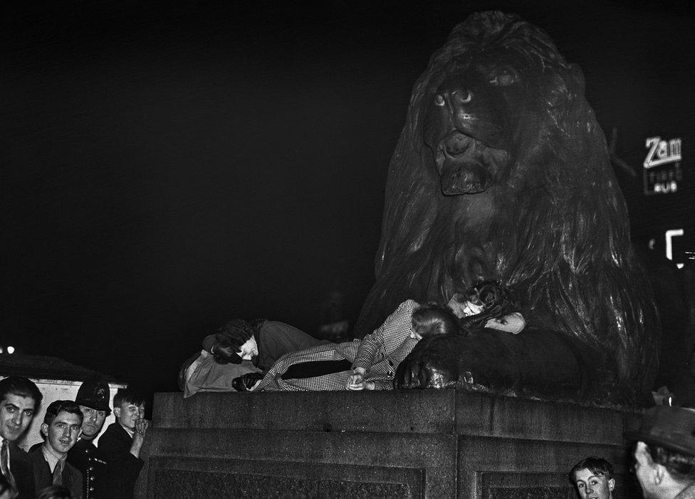 Revellers sleeping between the paws of one of Sir Edwin Landseer's lions at the base of Nelson's Column after celebrating the coronation of George VI and Queen Elizabeth