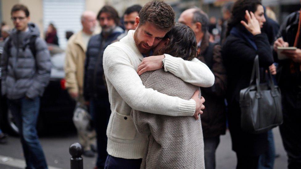 People react in front of the Carillon cafe and the Petit Cambodge restaurant in Paris Saturday Nov. 14, 2015,