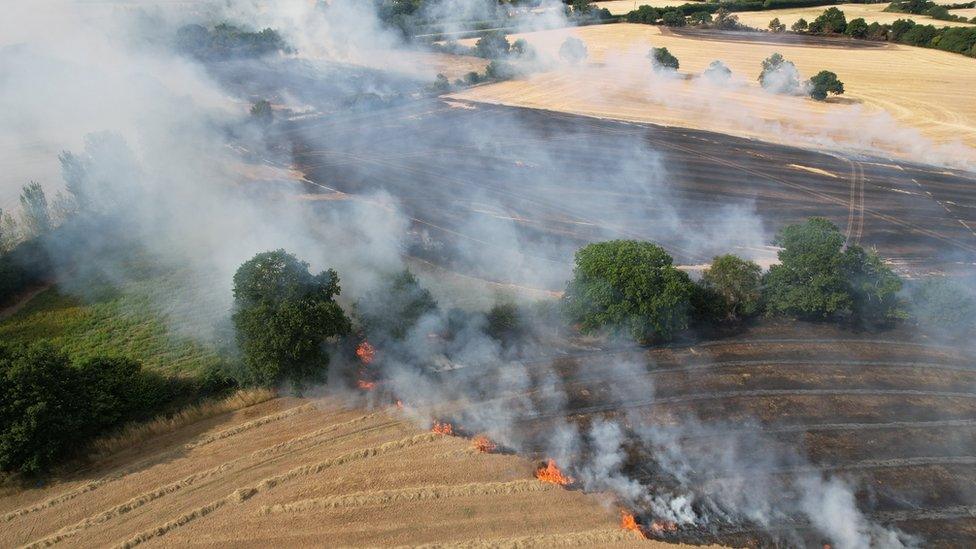 Ariel image of a field that has been burned by fire which is still burning with lots of smoke