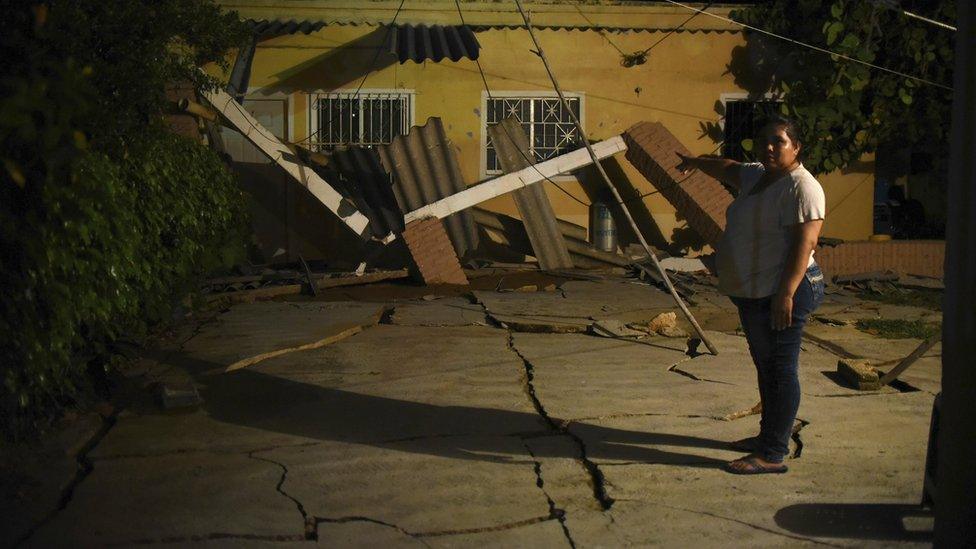 Woman pointing at damaged house