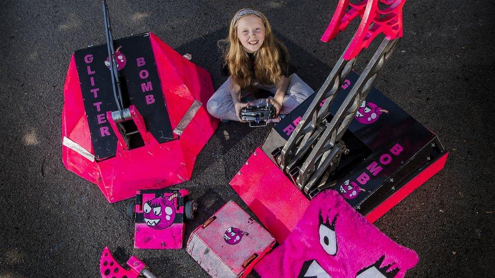 Eleven-year-old April Prince sitting beside her two robots