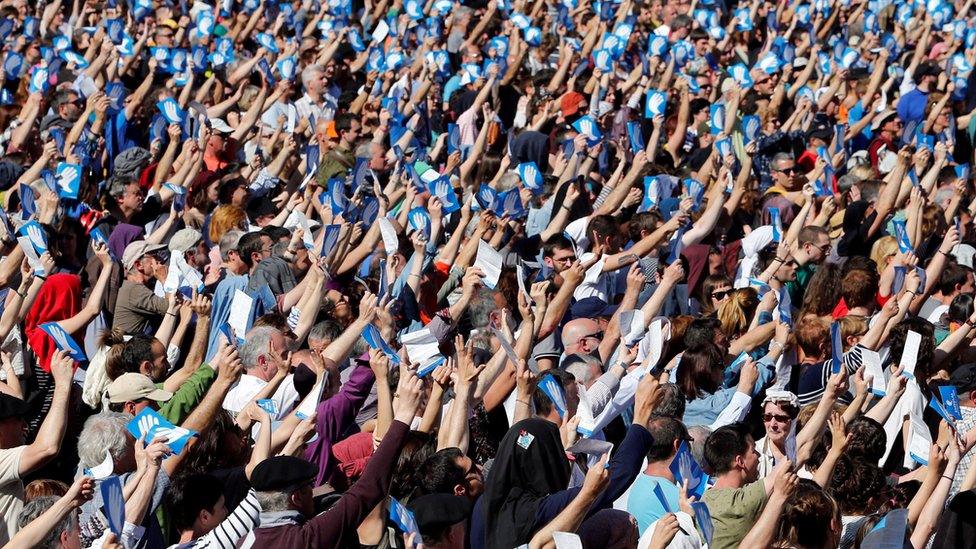 People hold up symbols of the "Artisans Of Peace" while attending a rally following Eta's announcement, Bayonne, 8 April 2017