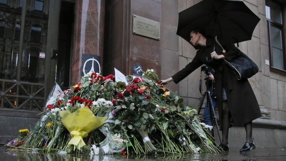 A woman lays flowers in front of the French consulate in St. Petersburg, Russia (14 November 2015)