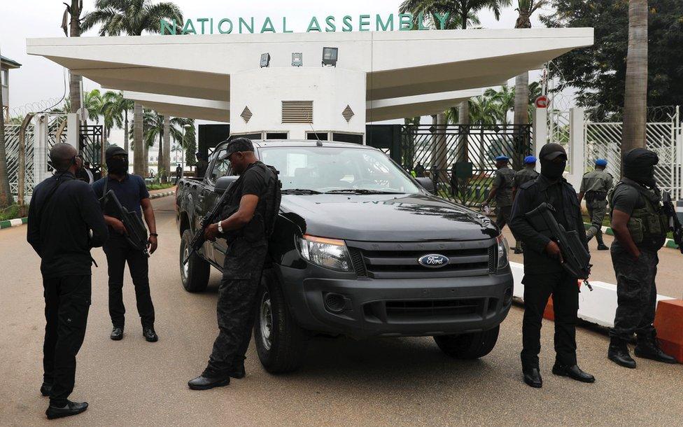 Armed men next to a vehicle