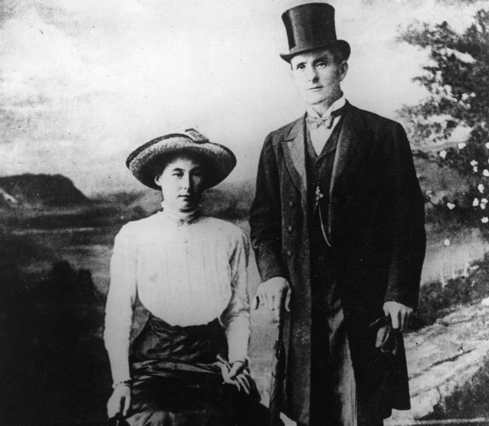 The 'Brides in the Bath' murderer George Joseph Smith (1872 - 1915) standing in front of a painted backdrop of the countryside with the first of his murder victims, Beatrice Mundy,