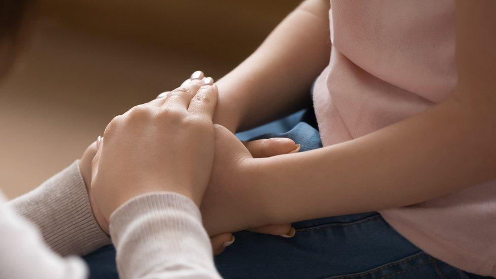 a woman holding a child's hands