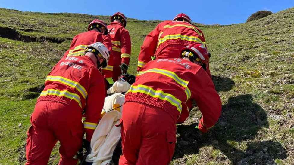 Firefighters climbing a hill with a patient