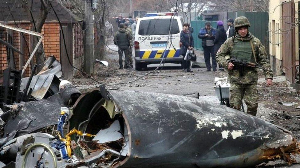 A soldier walks past the debris of a military plane that was shot down overnight in Kiev, Ukraine, 25 February 2022