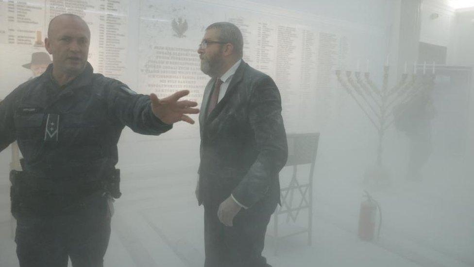 Grzegorz Braun looks on after using a fire extinguisher to put out Hanukkah candles at the parliament in Warsaw on 12 December